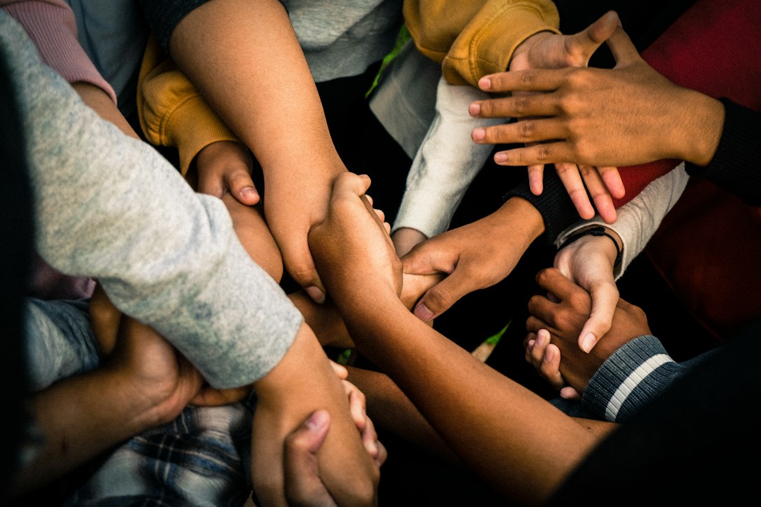 a-group-of-people-holding-hands-emb60hnhfl8