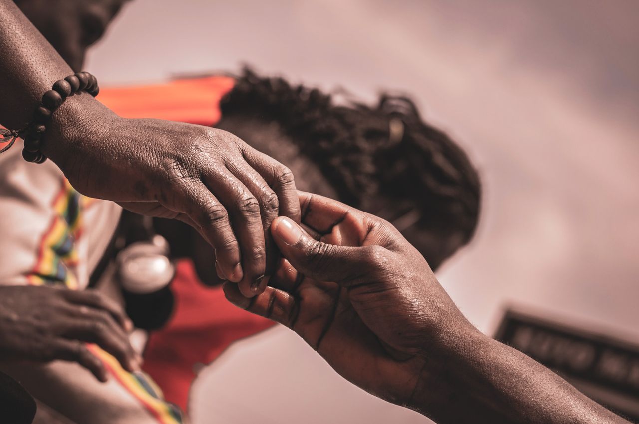 Detailed close-up of hands interacting outdoors, with a blurred background suggesting connection.