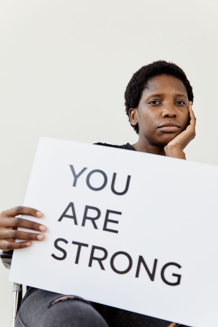 Portrait of a woman holding a sign reading You Are Strong promoting empowerment and resilience.